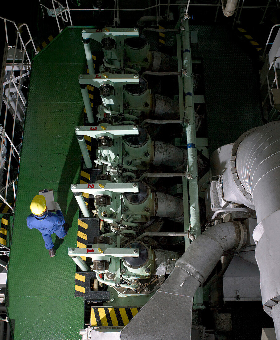 Luftaufnahme des Ingenieurs mit Wartungsplan im Maschinenraum des Schiffs, der eine Überprüfung durchführt