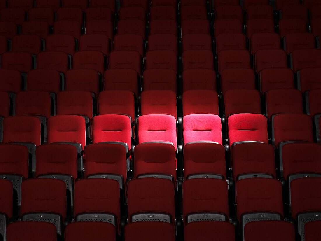 Scheinwerfer auf leere rote Sitze im Theater