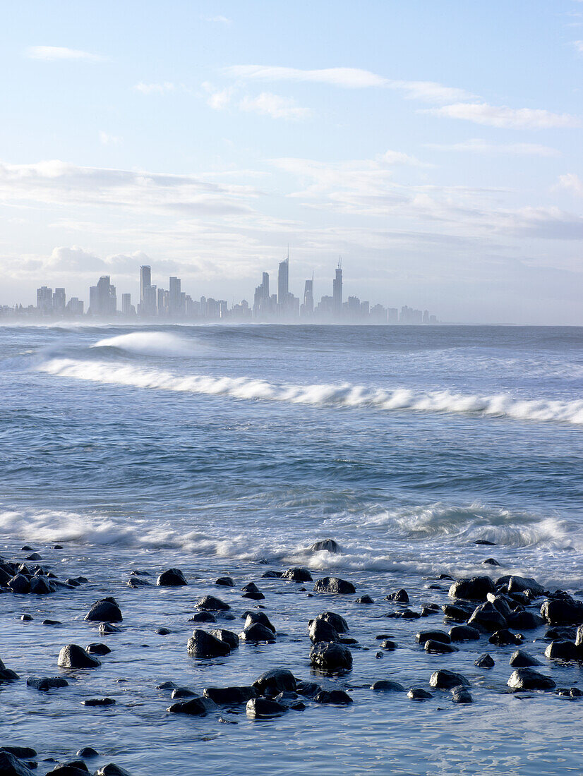 Looking across the waves and sea towards the city and coastline of Surfers Paradise