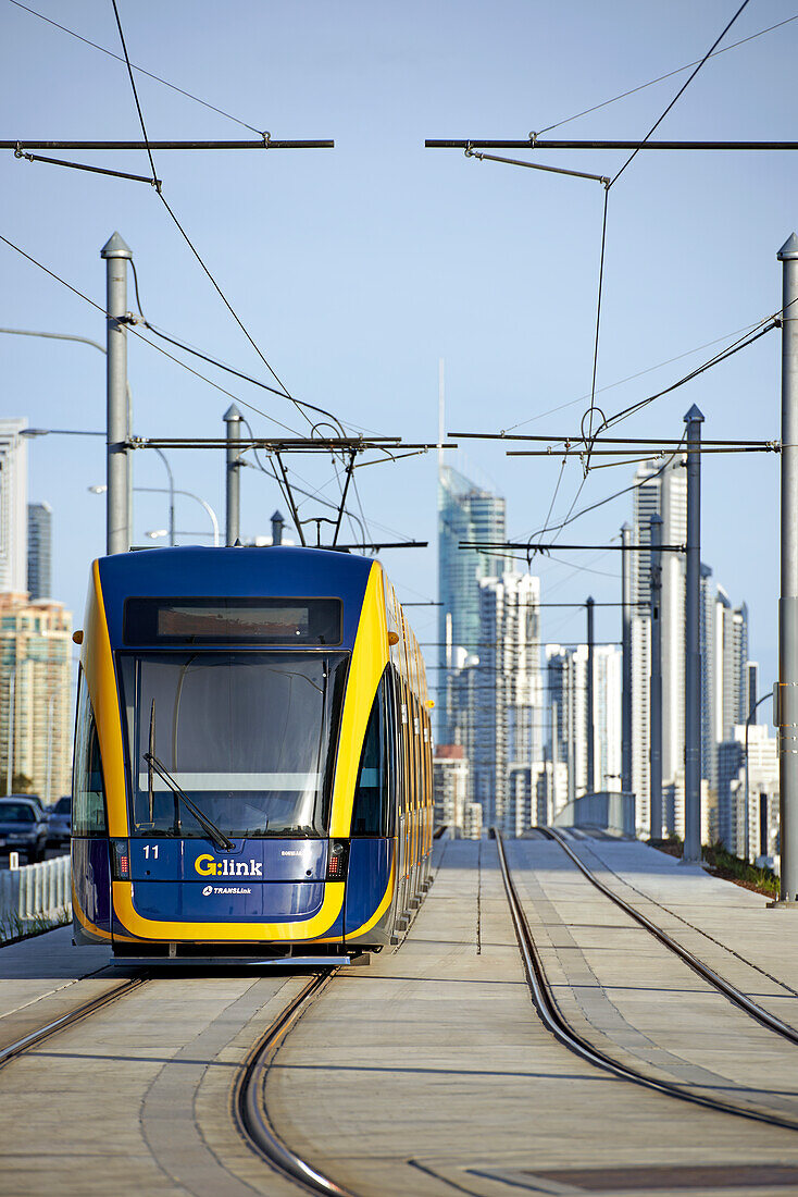 Tram travelling on lines and Surfers Paradise city in the background