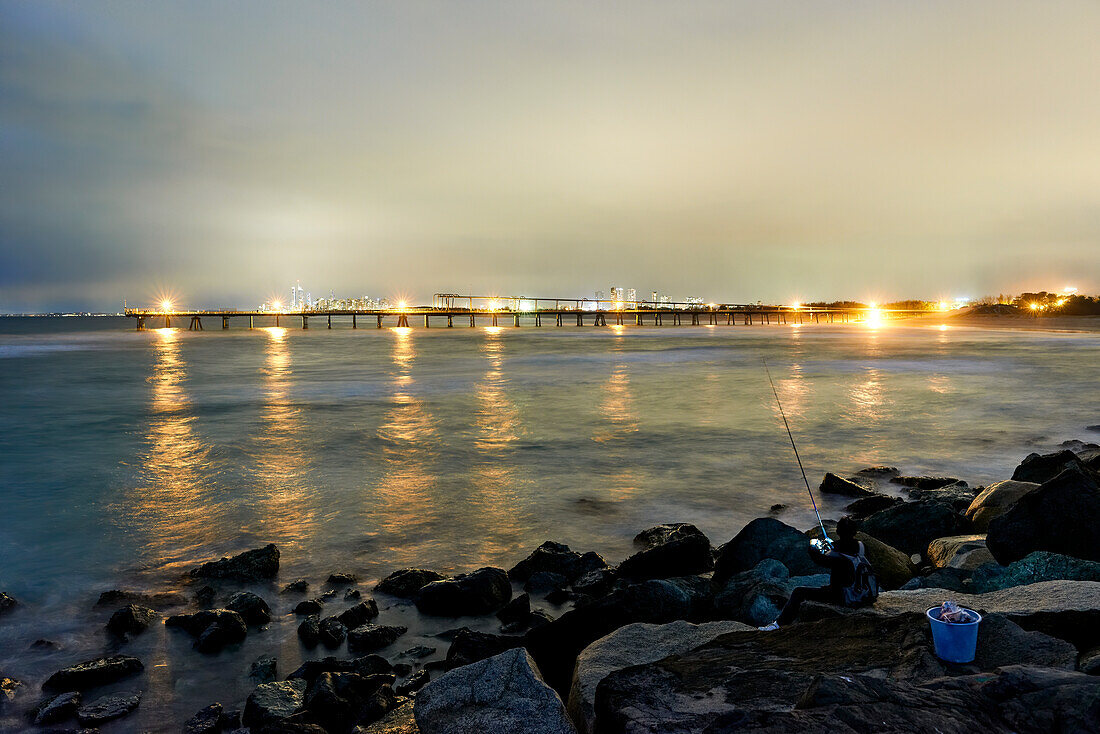 Evening shot looking across from The Spit over water and past the jetty to Surfers Paradise city lit up