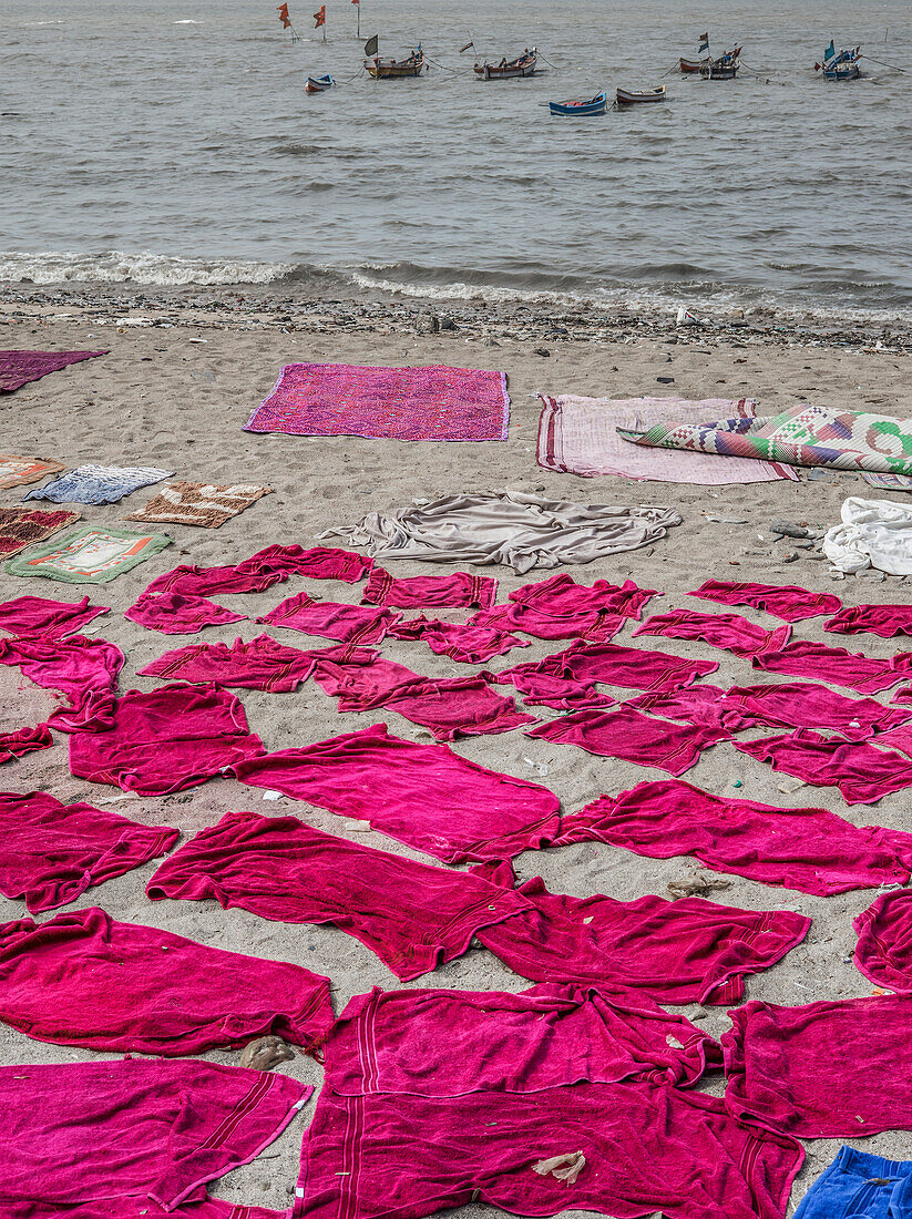Am Strand von Mumbai liegen rosafarbene Handtücher