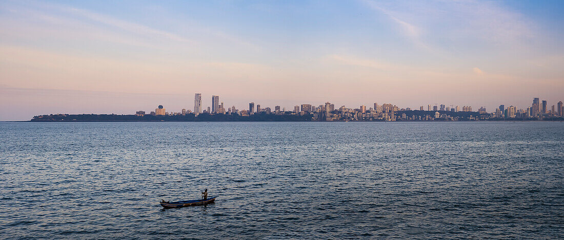 Blick über das Wasser mit einem einsamen Boot auf die Skyline von Mumbai City