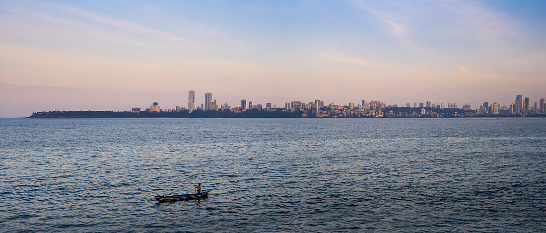 Looking across the water with lone boat to the Mumbai City skyline