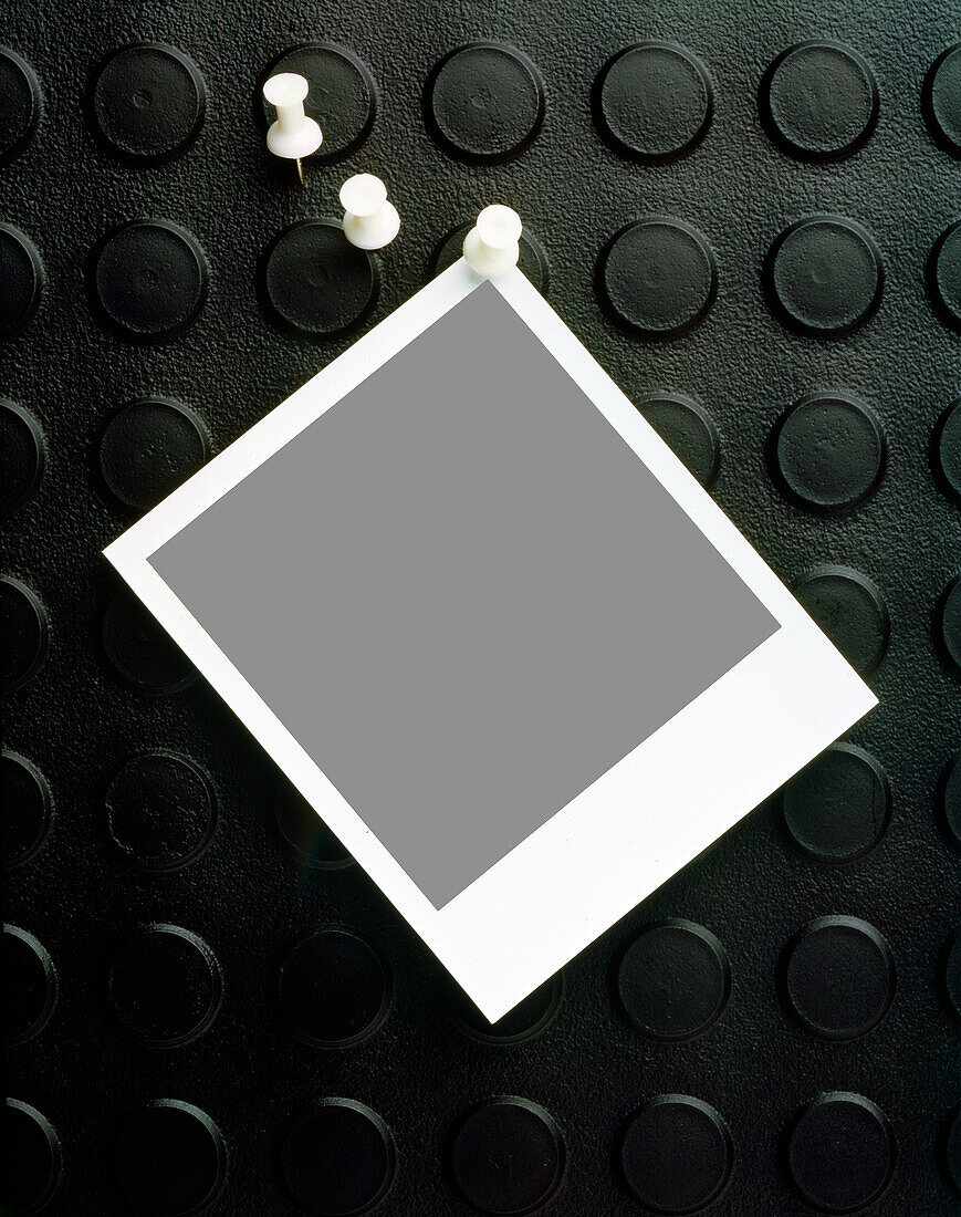 Leeres Polaroid, das an eine Pinnwand aus Gummi geheftet ist
