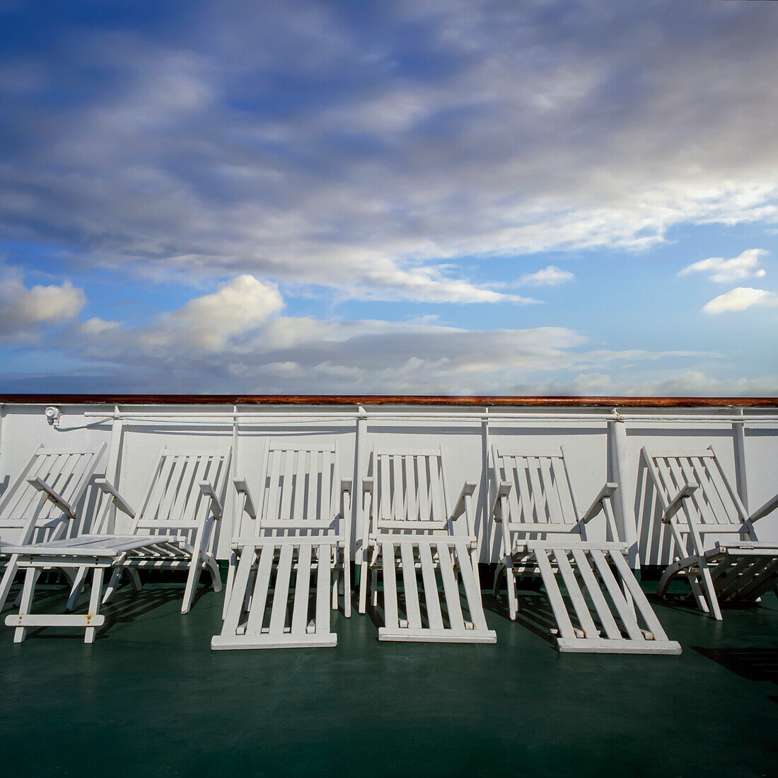Reihe von weißen Liegestühlen auf dem Deck des Kreuzfahrtschiffes