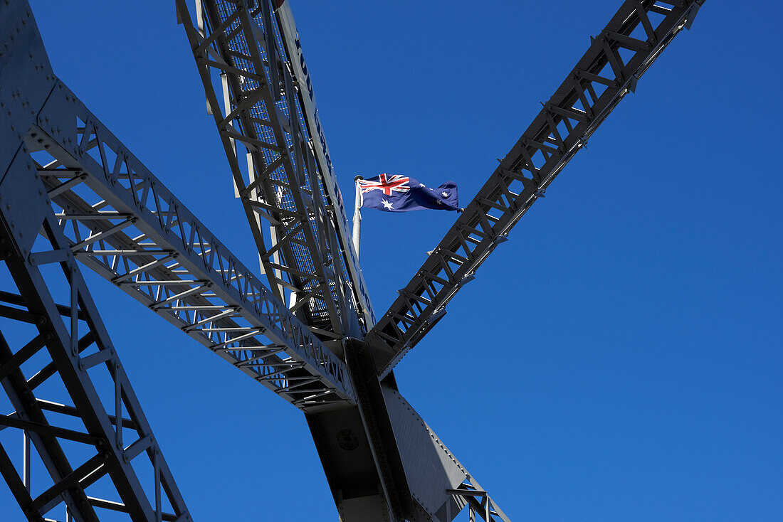 Australian Flag flying on top of Storey Bridge against blue sky