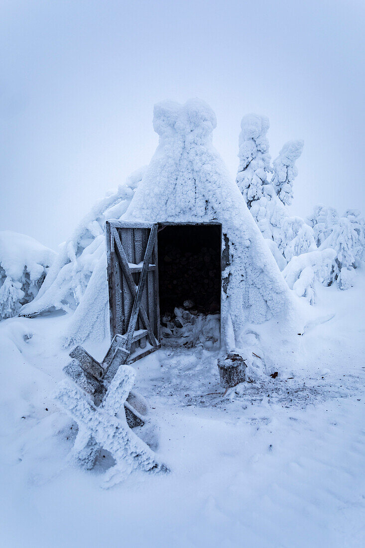 Ein Holzschuppen mit offener Tür nach einem Schneesturm in Finnisch-Lappland, Winterszene