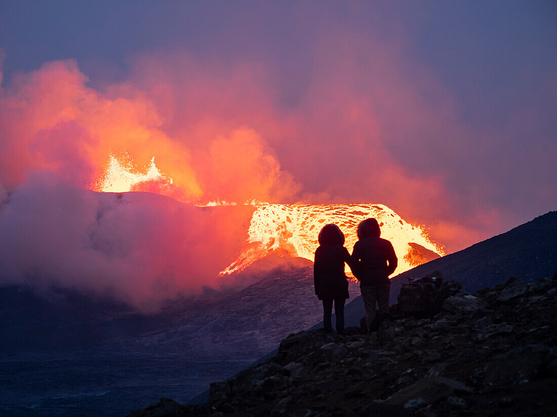 Paar genießt den Ausbruch des Vulkans Fagradalsfjall vom Beobachtungshügel aus, Island