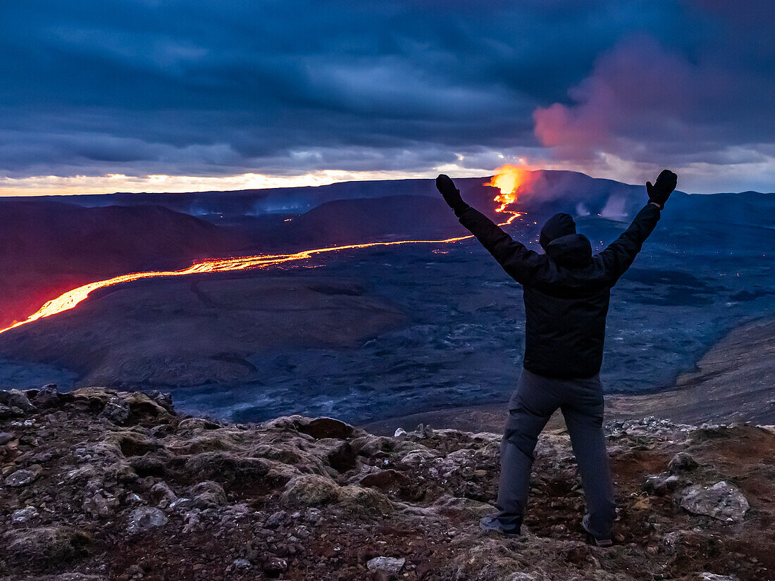 Celebration, Trekker views glowing river of magma and Fagradalsfjall Volcanic eruption at Geldingadalir, Iceland