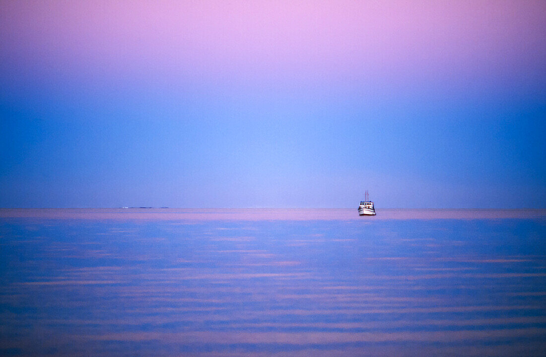 Boot auf tropischem Ozean bei Sonnenuntergang