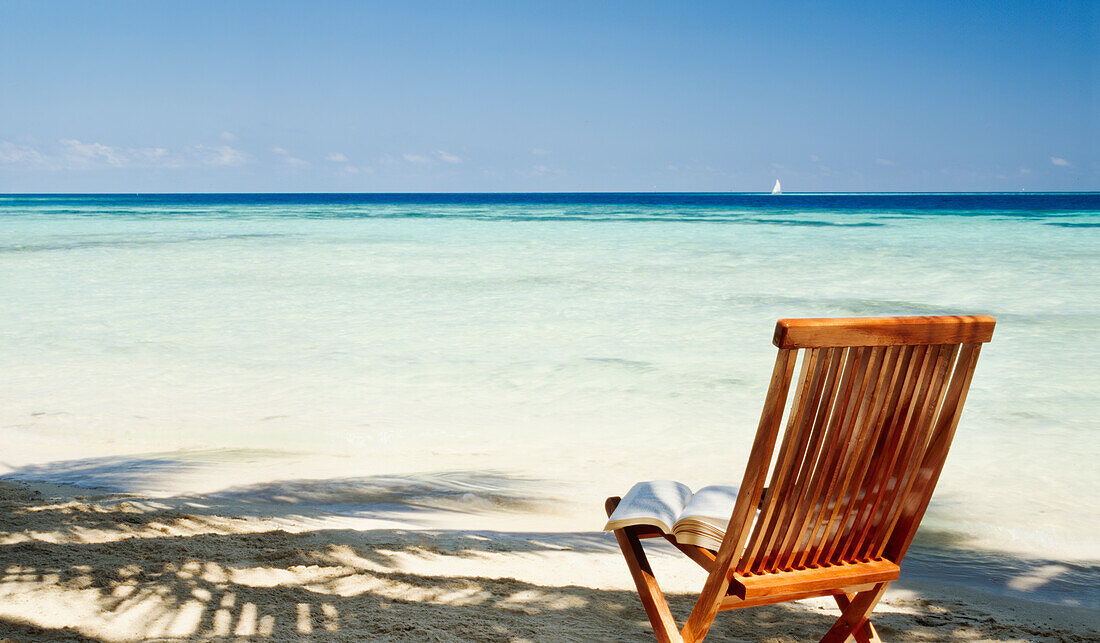 Buch auf einem leeren Stuhl am tropischen Strand