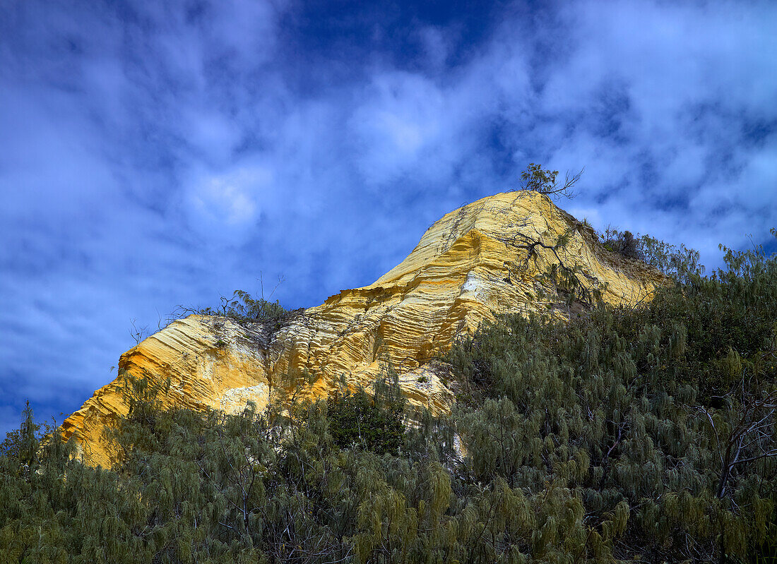 Exposed rock hillside looming up from native flora into the sky