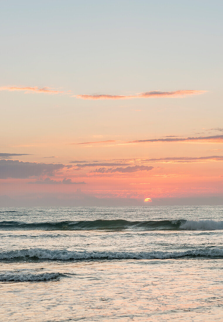 Sun setting on the horizon over peaceful ocean