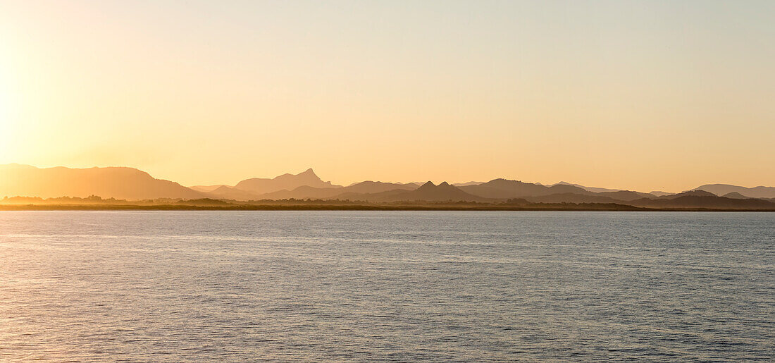Looking over water towards Mount Warning and hills from Byron Bay at dusk