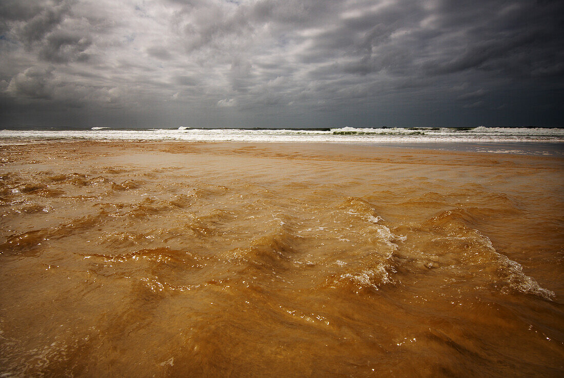 Murky waters running down to meet the sea on stormy day