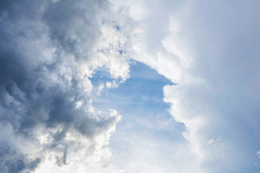 Wolken teilen sich und blauer Himmel bricht durch die Lücke