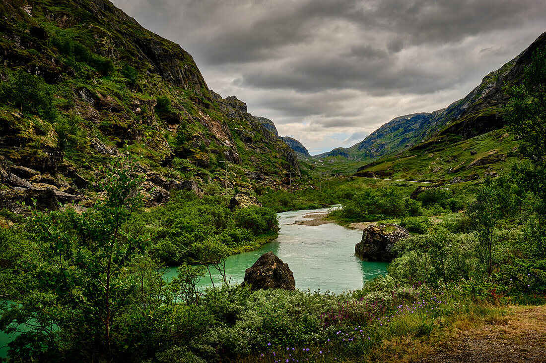 Sognefjellvegen in Norway, lonely country road, mountain river in front of a rock massif