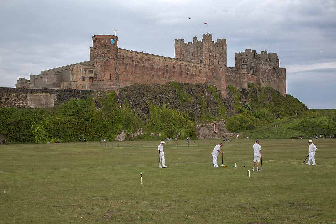Croquet player dressed in white in front of Bamburgh Castle, England. British