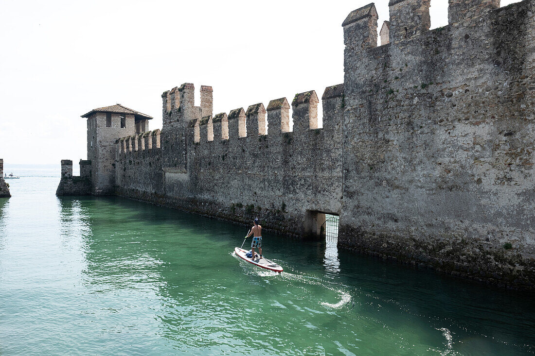 SUP Paddler vor dem Schloss von Sirmione, Verona District, Venetien, Italien