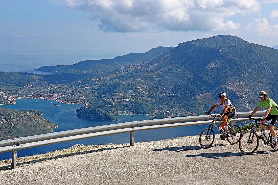 Cyclists on a quiet Ithaca island road, here overlooking Vathy Bay, Ithaca, Ionian Islands, Greece