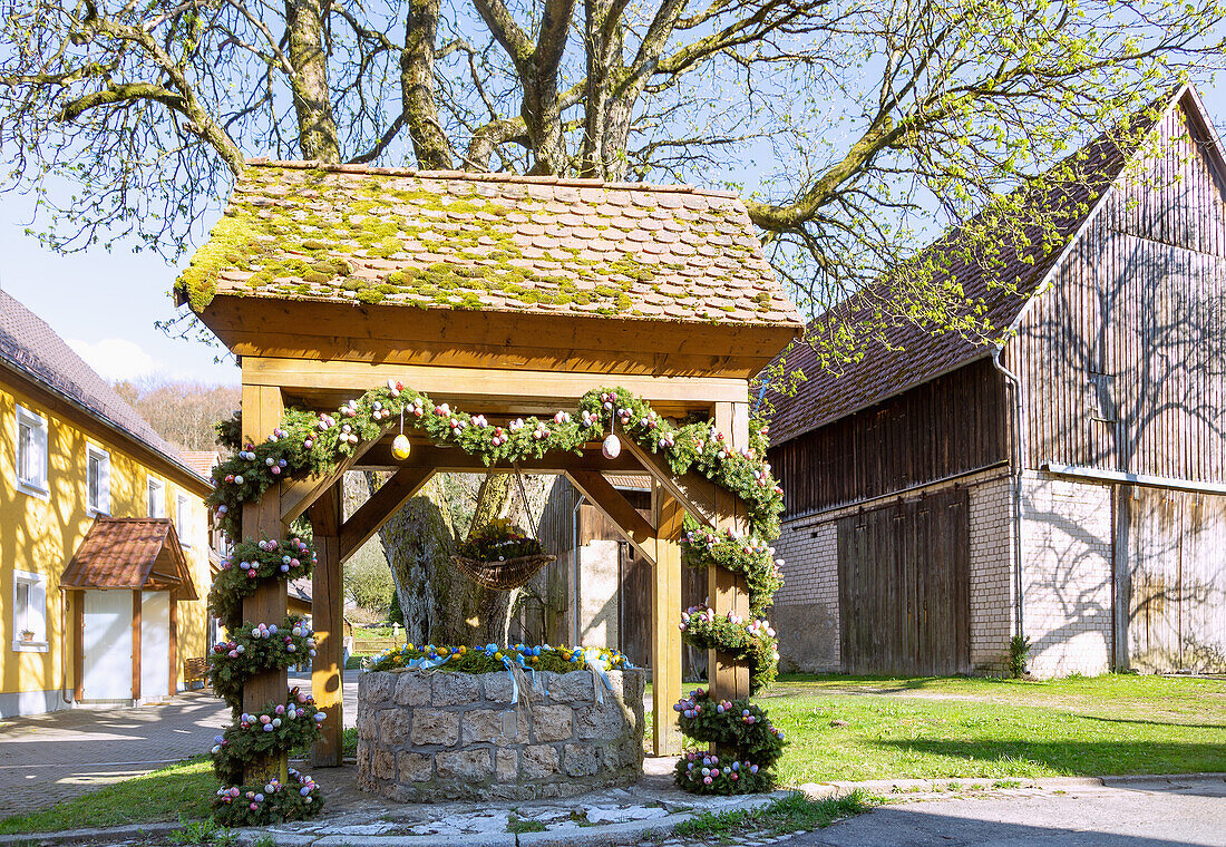 mit bunten Ostereiern geschmückter Osterbrunnen in Wohlmuthshüll in der Fränkischen Schweiz, Bayern, Deutschland