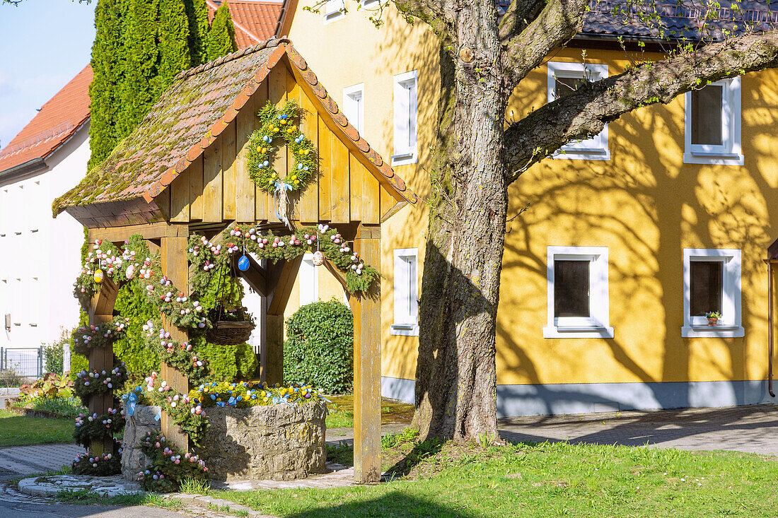 mit bunten Ostereiern geschmückter Osterbrunnen in Wohlmuthshüll in der Fränkischen Schweiz, Bayern, Deutschland