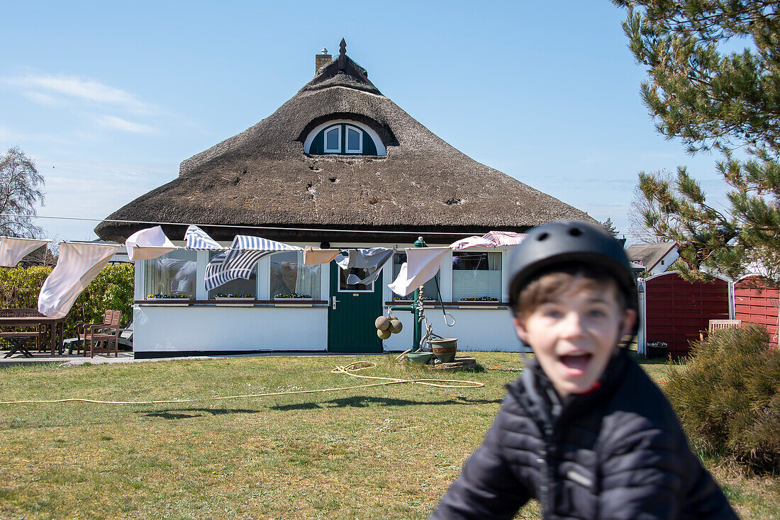 Laundry flapping in the wind, thatched house, boy with bicycle helmet, Neuendorf, Hiddensee Island, Mecklenburg-West Pomerania, Germany