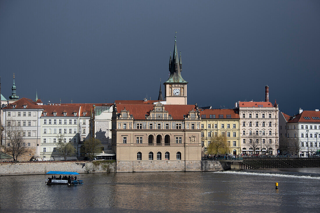Dark rain clouds, Old Town buildings, excursion boat on the Vltava River, Prague, Czech Republic