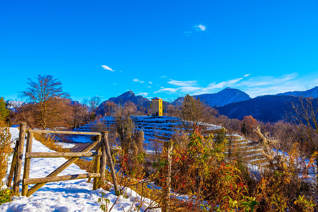 Weinberg und ein Tor mit Schnee im Winter und Sonnenstrahl in Collina d'Oro mit Berg in Lugano, Tessin in der Schweiz