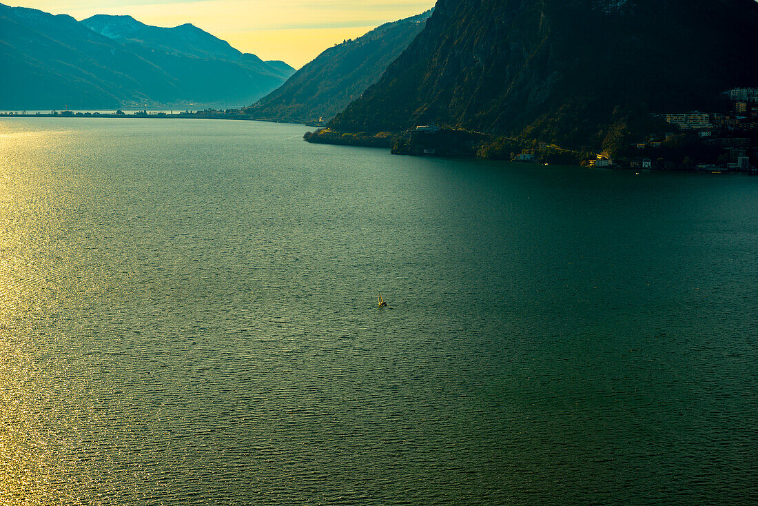 Sailing Boat on Alpine Lake Lugano with Sunlight and Mountain in Lugano, Ticino in Switzerland.