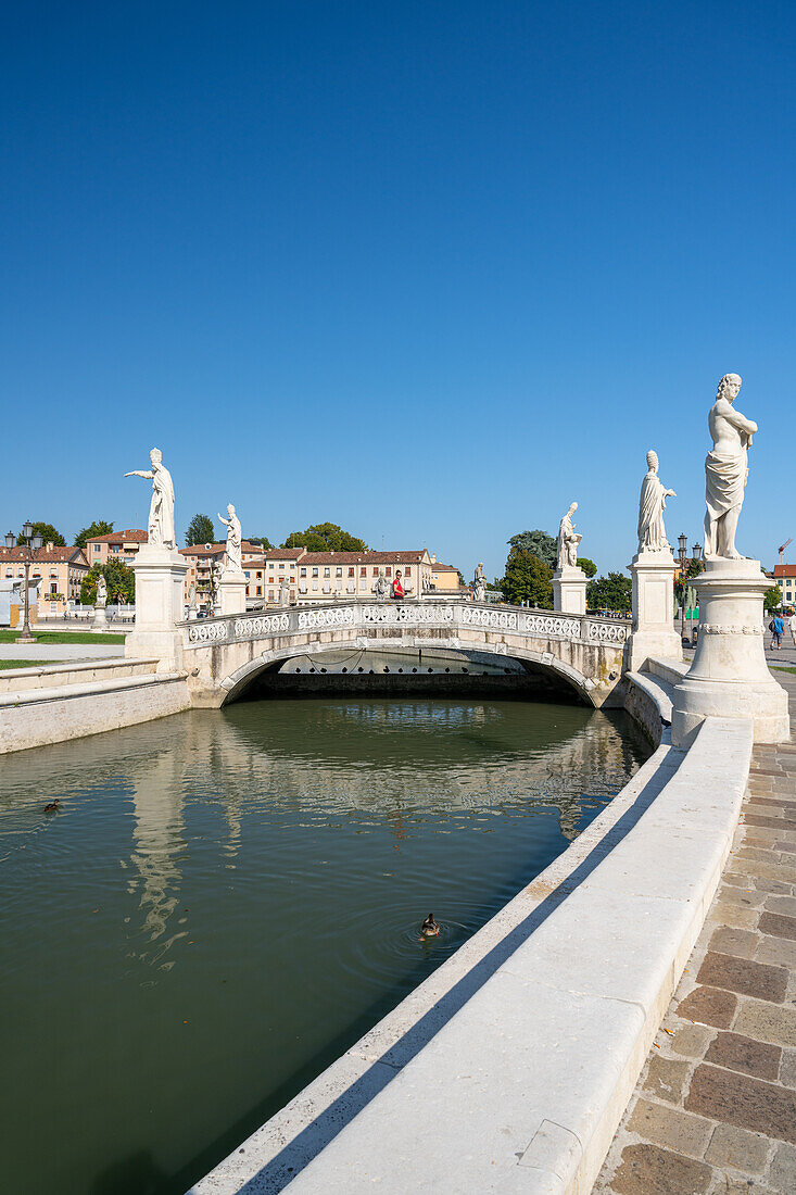 Moat and northern bridge on the public square with over 70 statues of historic townspeople at Prato della Valle, Padua, Italy.