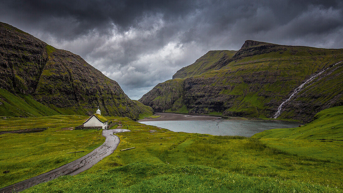 Kirche Saksun am Fjord, Streymoy, Färöer. Dunkle Wolken. Wasserfall. Einsam.