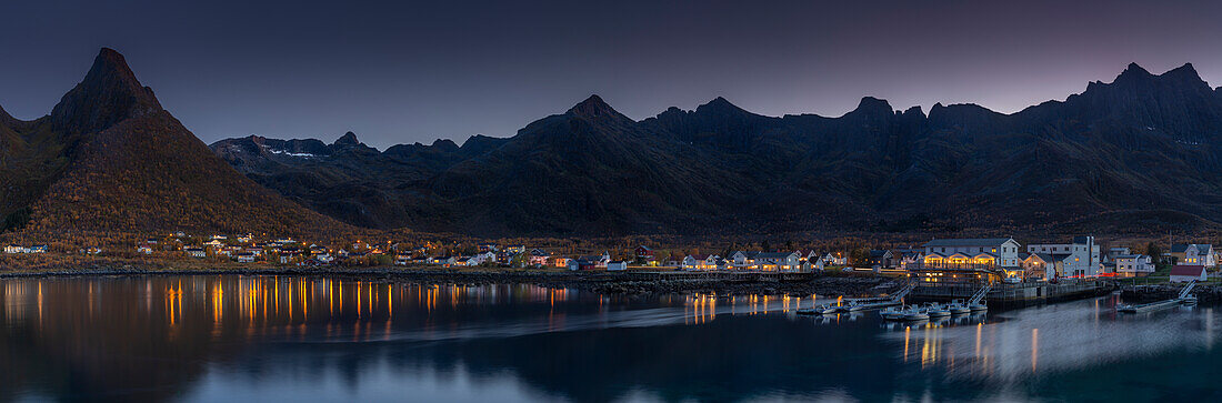 Abendlicher Panorama Blick auf beleuchtetes Dorf Mefjordvaer, Senja, Norwegen mit Berg Litjedalsvatnet