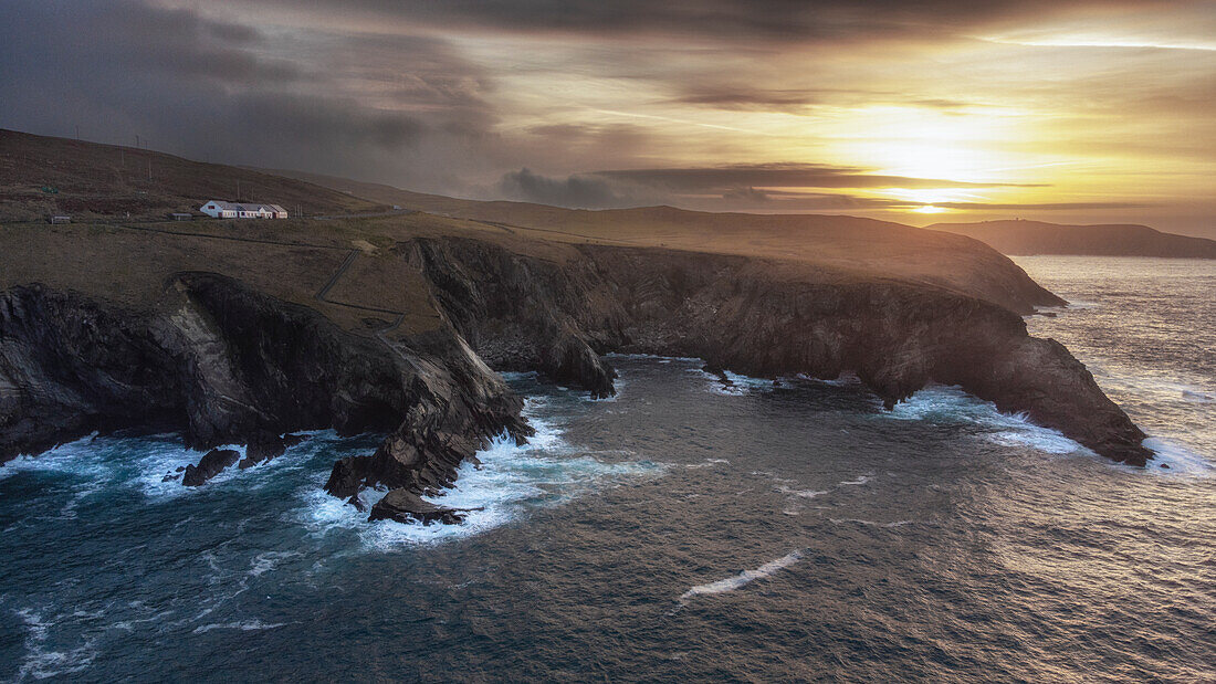 Sonnenaufgang am Besucherzentrum Mizen Head. Blick vom Meer auf Steilküste. Signal Station. County Cork, Irland.