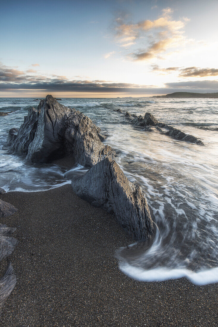 Surf laps rocks on Black Beach. Little Island Bay Beach, County Cork, Ireland.