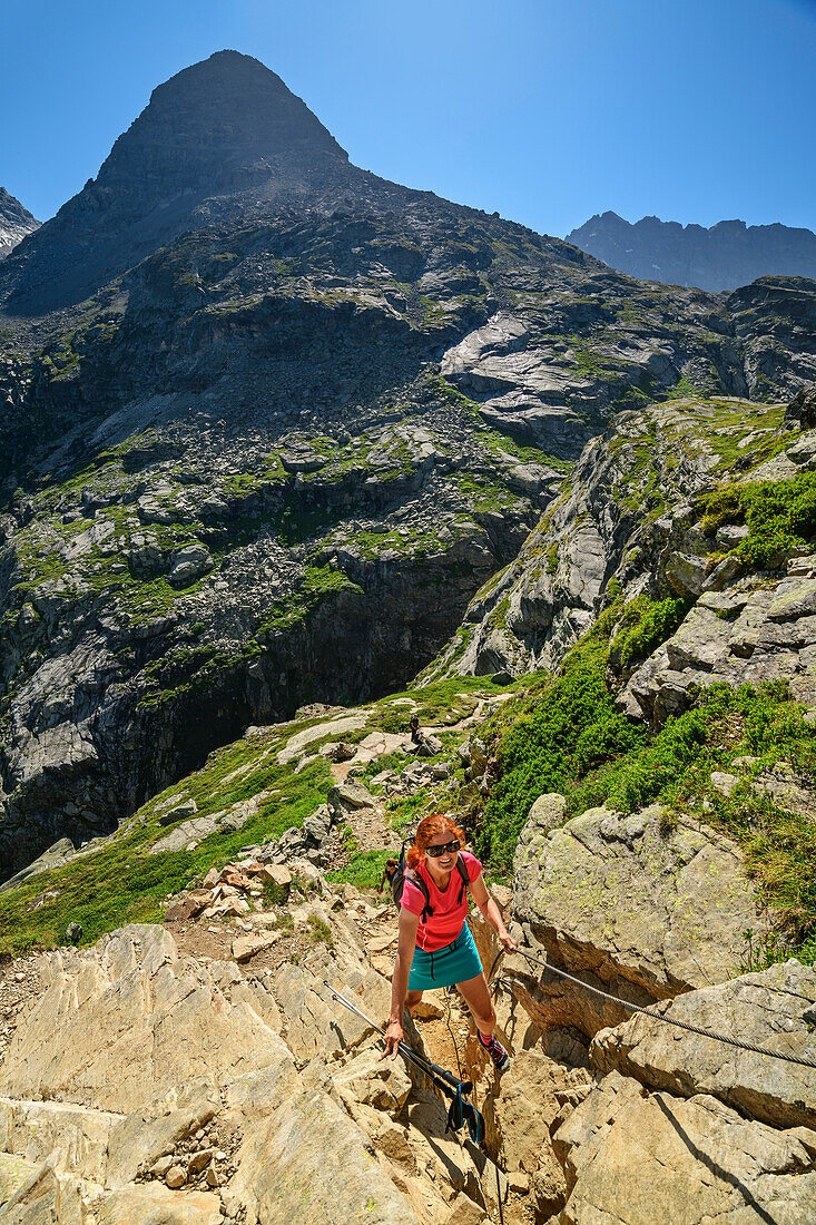 Woman hiking climbs via via ferrata to Refuge des Evettes, Vanoise National Park, Vanoise, Savoie, France