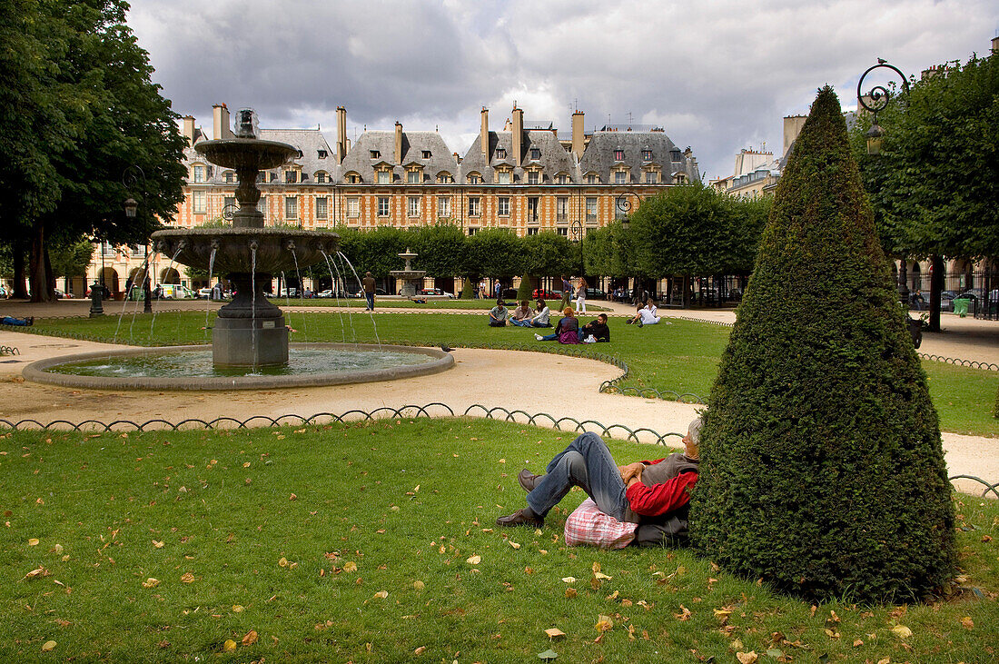 Man with his back to topiary and fountain,Place des Vosges, The Marais, Paris, France