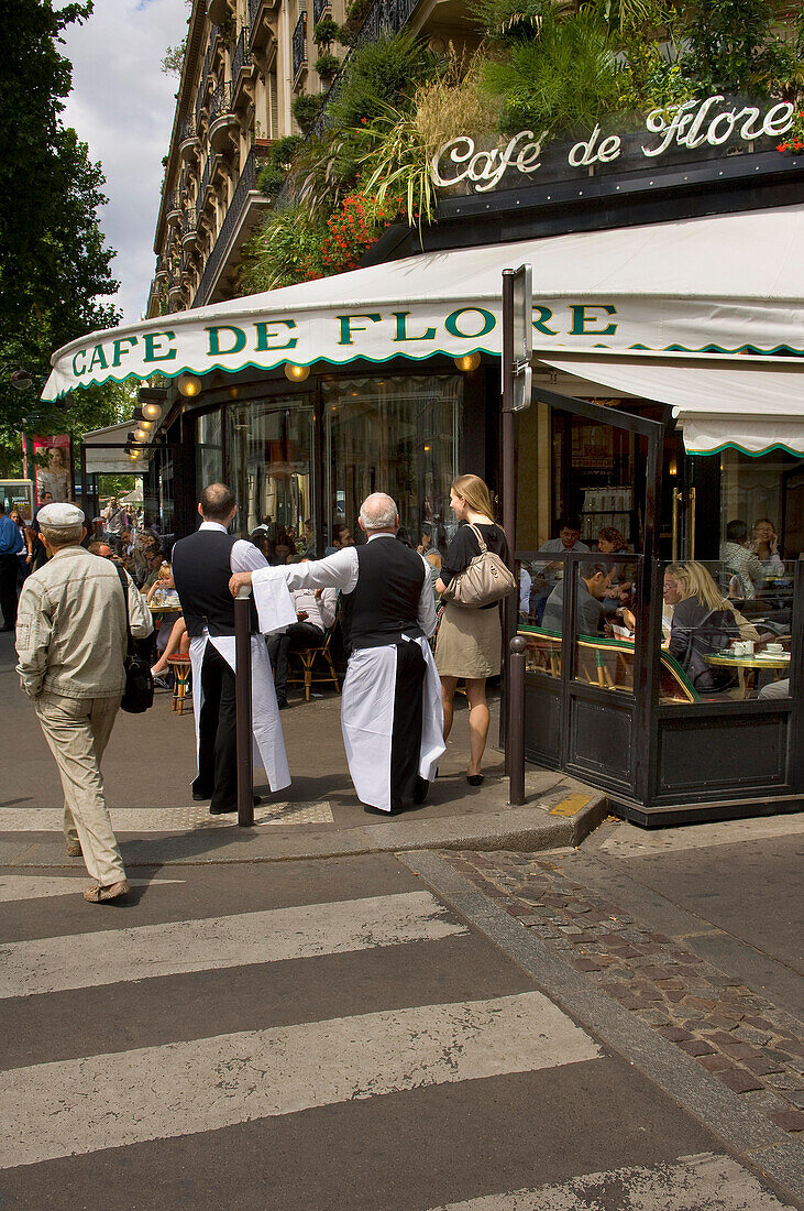 Waiters talking to a young woman and people sitting outside Cafe de Flore, Blvd St Germain, Paris, France
