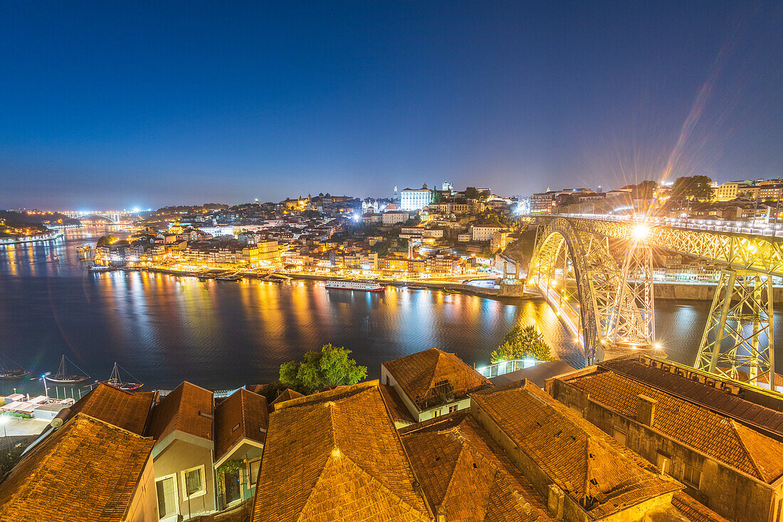 Dom Luís I half-timbered arch bridge over Douro river and historic old town at night in Porto, Portugal