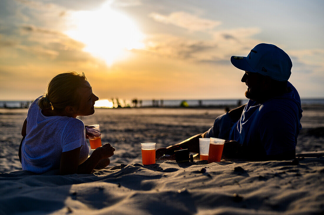 Man and woman enjoying sunset with a drink, Ording district, St. Peter Ording, North Friesland, North Sea coast, Schleswig Holstein, Germany, Europe