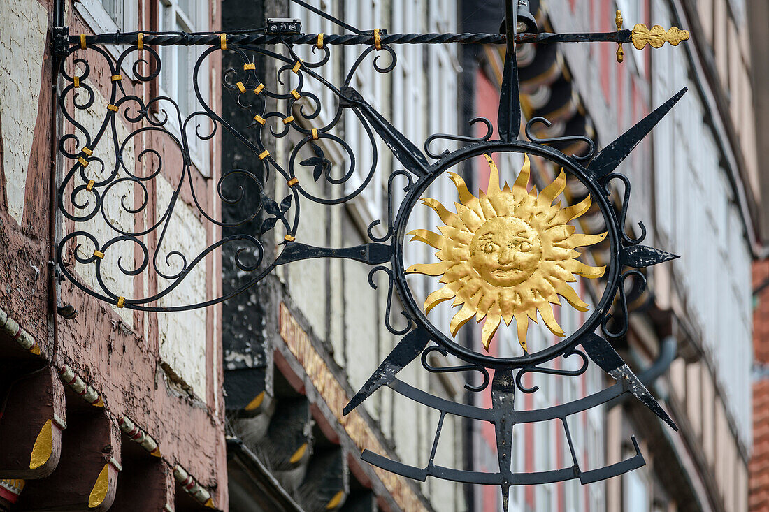 Wrought iron sun with half-timbered houses in the background, Celle, Heidschnuckenweg, Lower Saxony, Germany