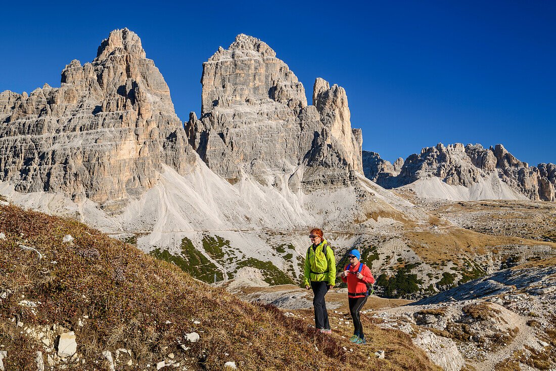 Mann und Frau beim Wandern mit Drei Zinnen im Hintergrund, am Monte Campedelle, Drei Zinnen, Dolomiten, UNESCO Weltnaturerbe Dolomiten, Venetien, Venezien, Italien