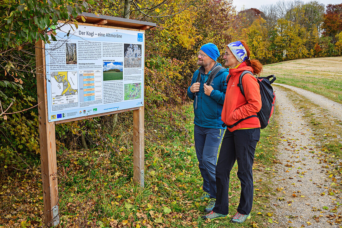 Man and woman hiking reading information board on the Holzkirchen Geology Trail, Holzkirchen geo-teaching trail, Upper Bavaria, Bavaria, Germany