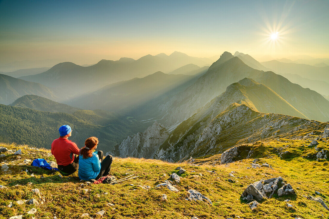 Man and woman hiking sitting on the summit and looking over the Karawanken, Veliki vrh, Hochturm, Karawanken, Slovenia, Carinthia, Austria