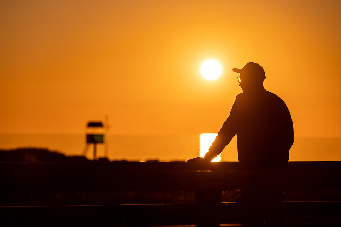 Junger Mann bei Sonnenuntergang auf der Seebrücke in Heiligenhafen, Heiligenhafen, Ostsee, Ostholstein, Schleswig-Holstein, Deutschland