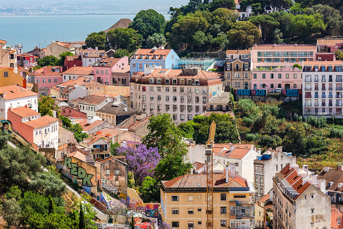 Bunte Gebäude und Parks entlang von Hügeln, vor dem Tejo in Lissabon, Portugal