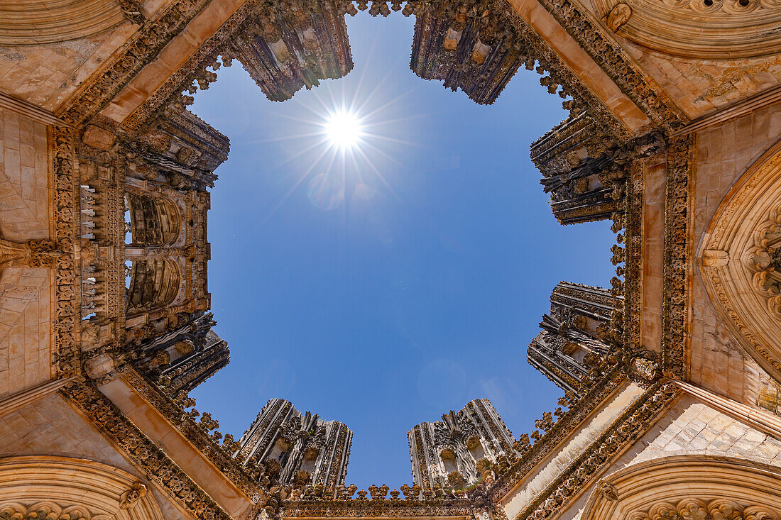 Sonnenstern im Gegenlicht über den prachtvollen unvollendeten Kapellen vom Kloster Batalha mit Ultraweitwinkel, Portugal