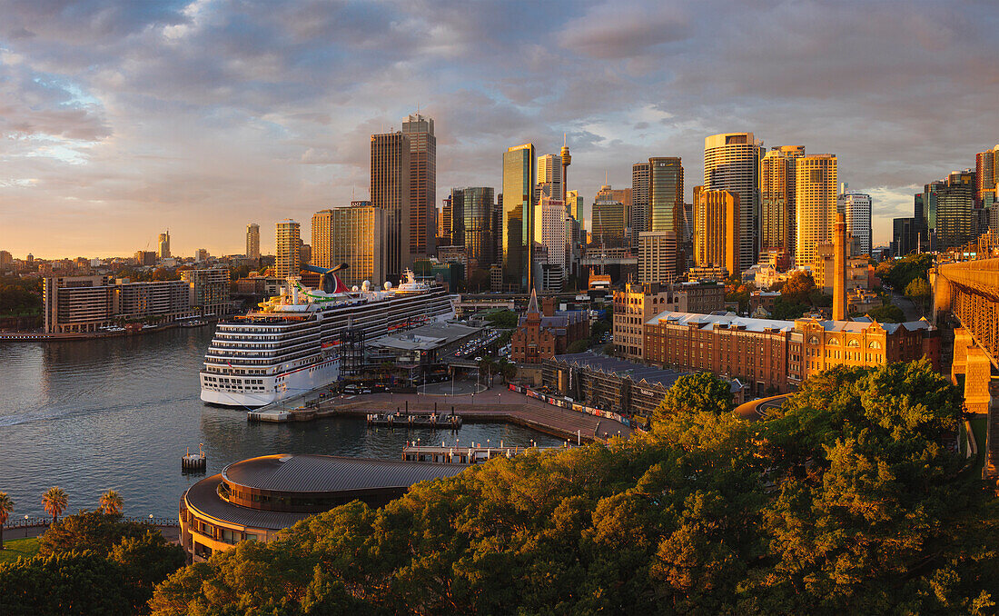 Kreuzfahrtschiff im Hafen von Sydney mit Wolkenkratzern im Hintergrund
