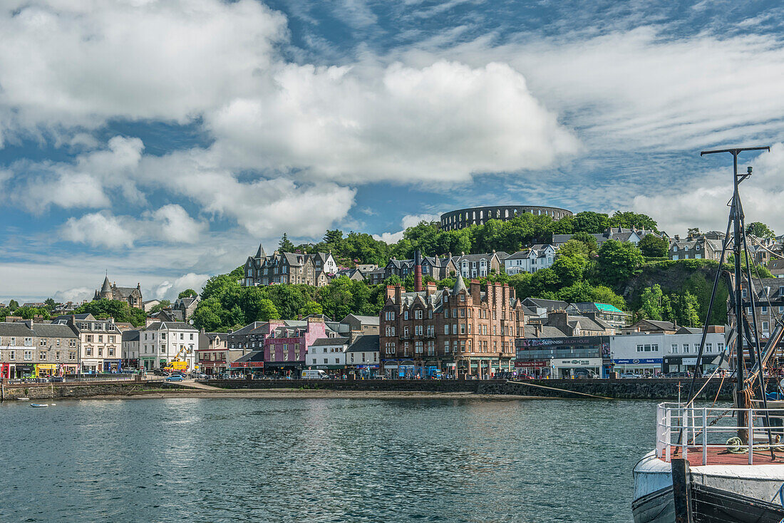 Waterfront town with Coliseum-style monument on hilltop, Mccaig's Tower and Battery, UK